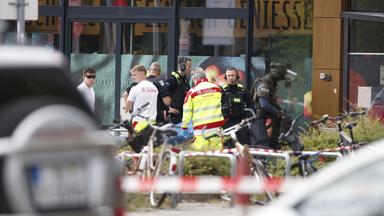 11.07.2026, Berlin: Einsatzkräfte stehen vor einem Supermarkt neben einer verletzten Person auf einer Trage.