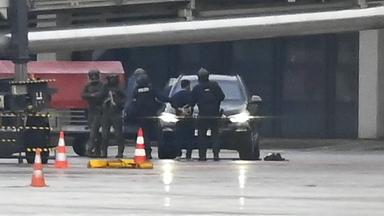 Ein Mann wird auf dem Flughafen von der Polizei weggeführt. 