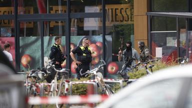 Einsatzkräfte stehen am 11.07.2026 vor einem Berliner Supermarkt, in dem ein Mann seit dem Vorabend eine Frau als Geisel hält.