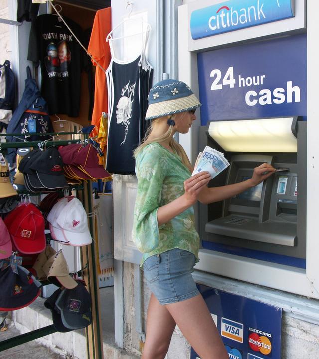 Frau hebt Geld an einem Automaten im Ausland ab.