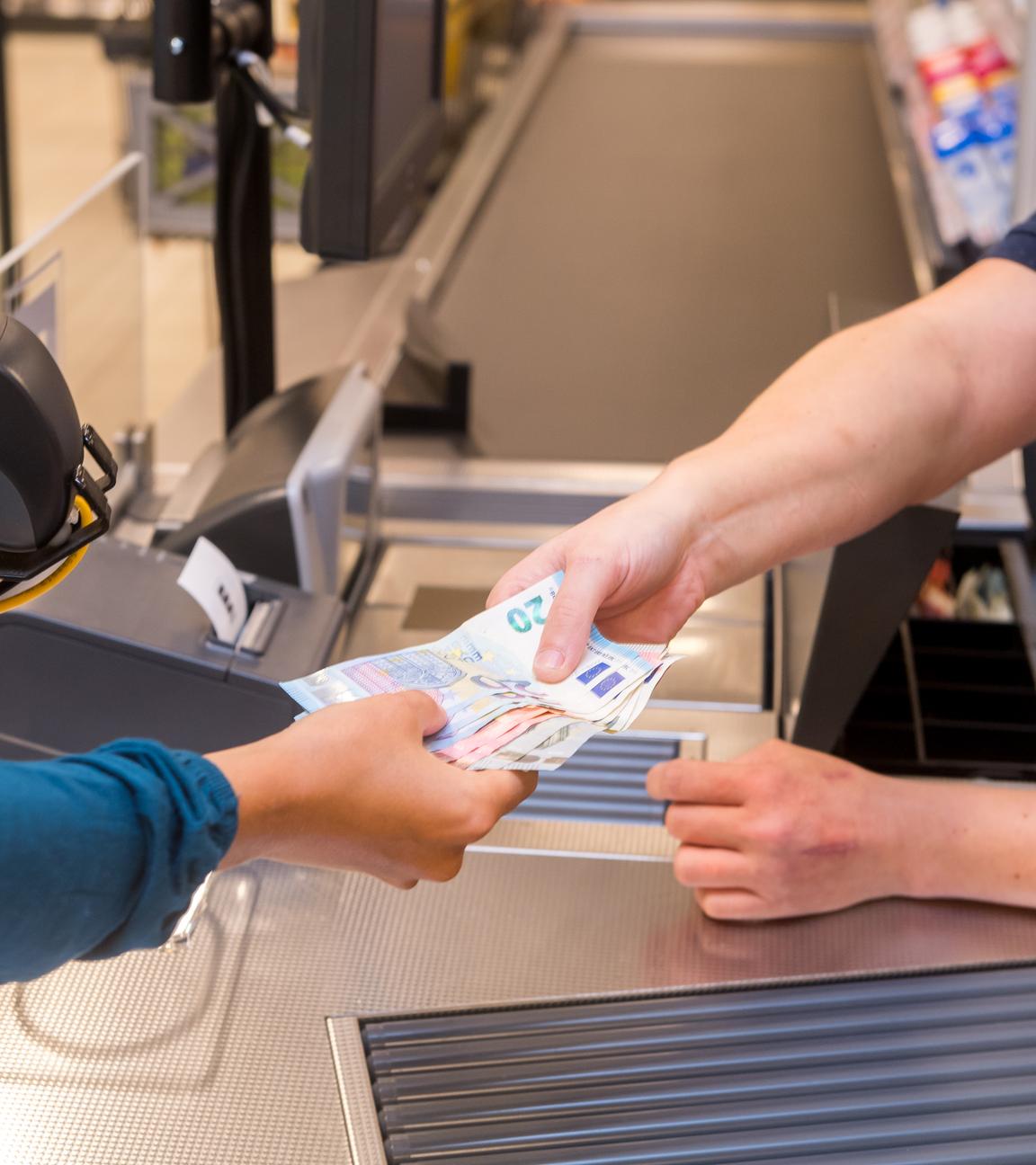Schleswig-Holstein, Flensburg: ILLUSTRATION - In einem Supermarkt hebt eine Kundin beim Bezahlen auch gleich Bargeld ab.