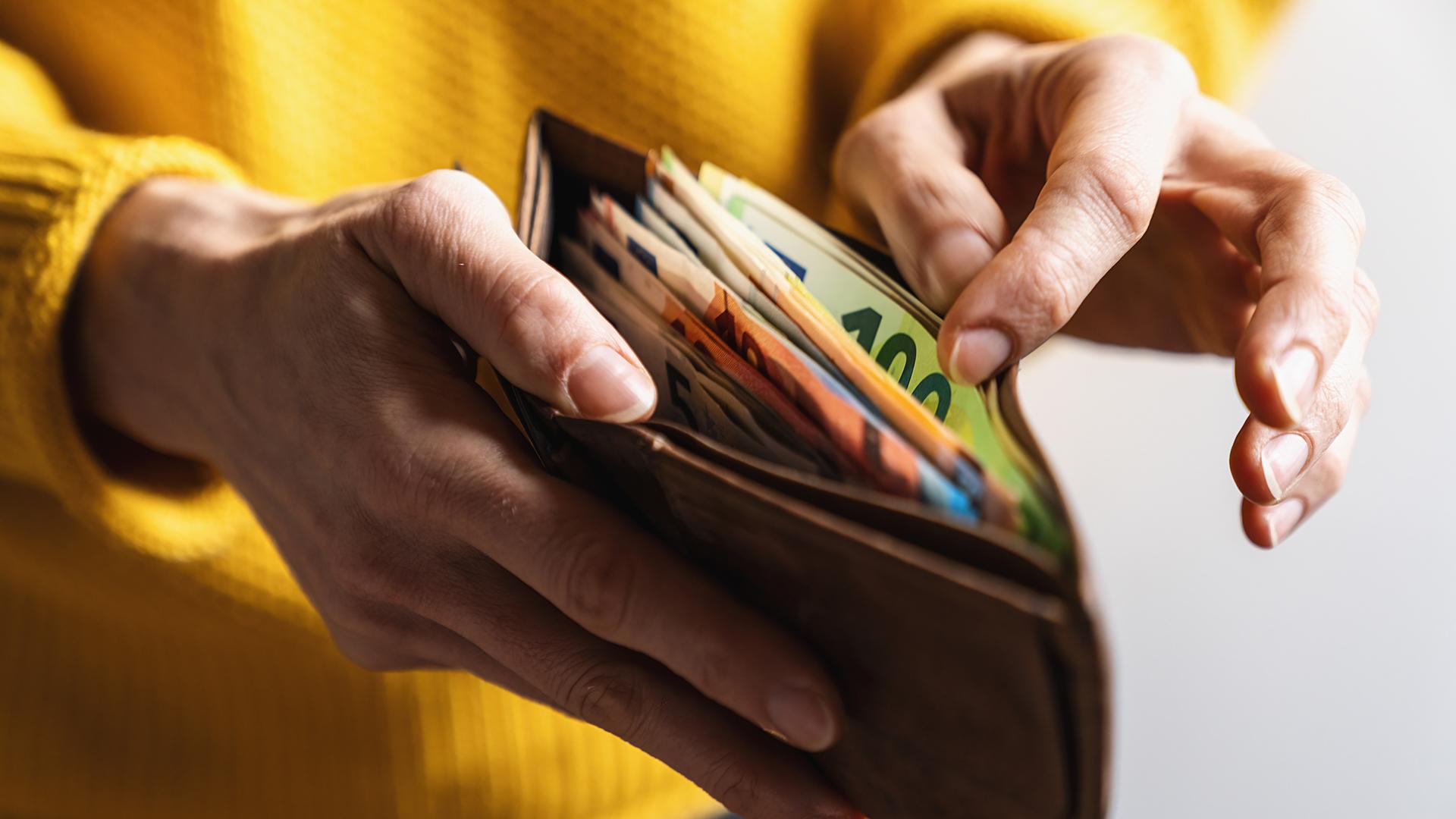 Eine Frau zählt Geldscheine in ihrem Portemonnaie.