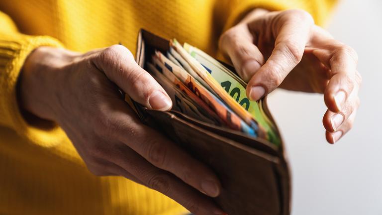 Eine Frau zählt Geldscheine in ihrem Portemonnaie.