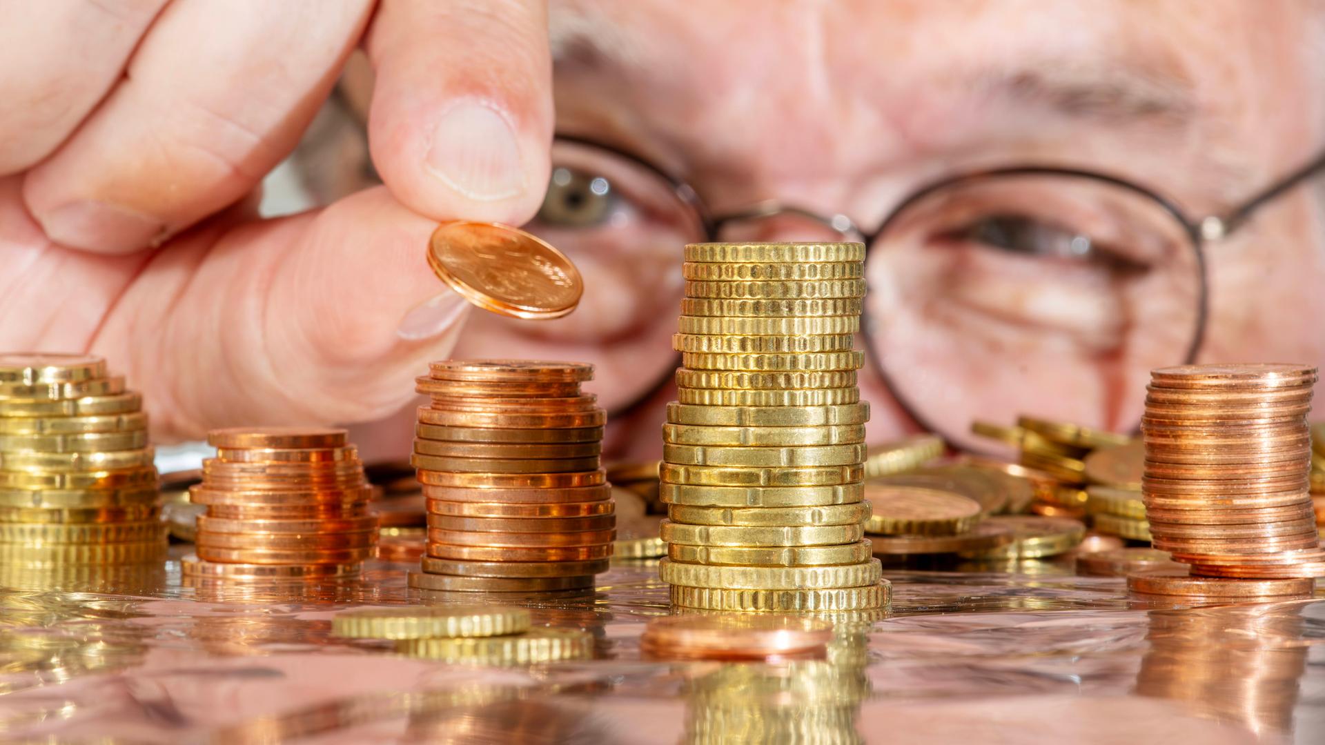 Ein Mann stapelt Münzen auf einem Tisch.