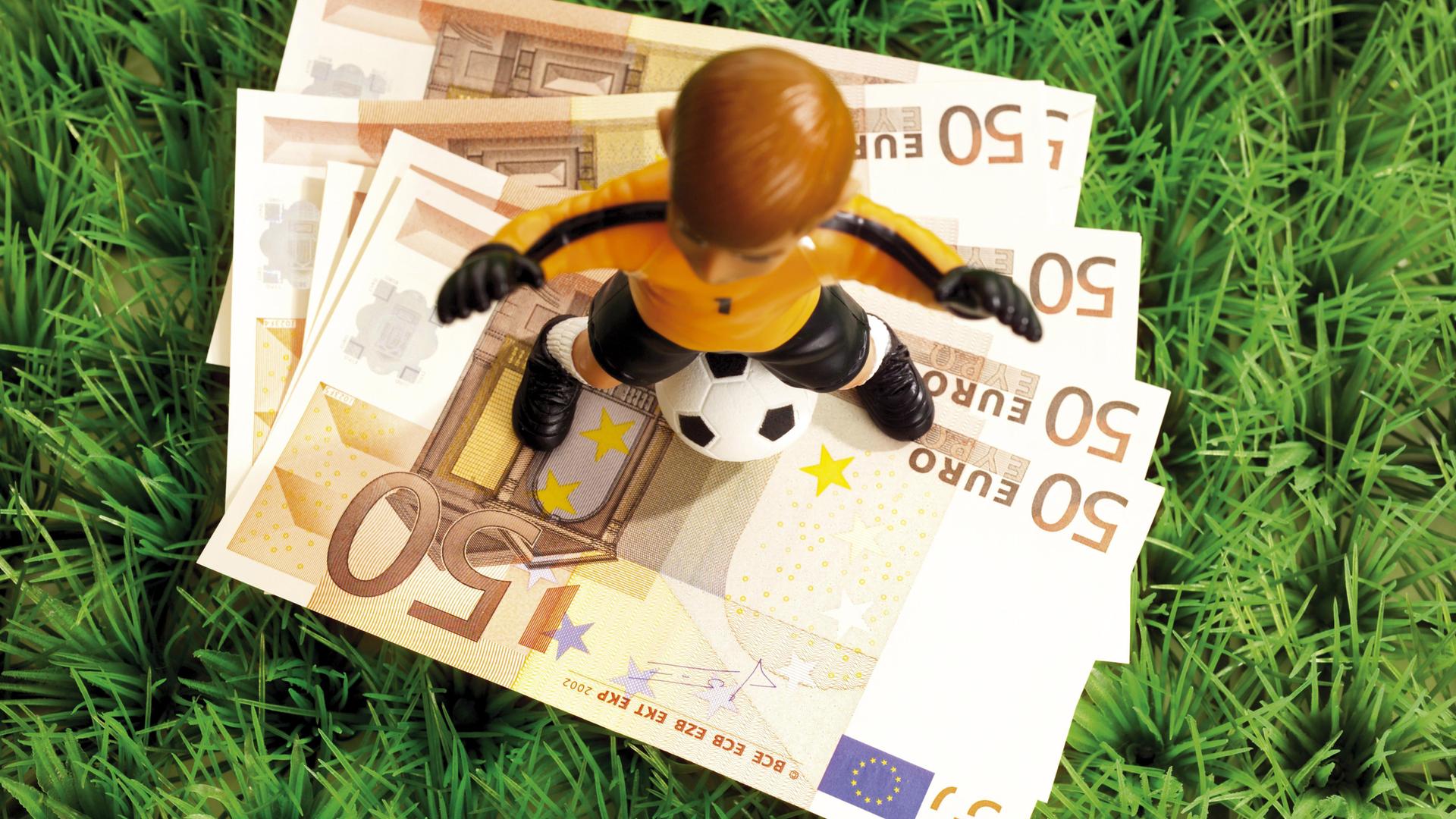 Illustration: Spielfigur eines Fußballers steht auf Geldscheine