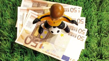 Illustration: Spielfigur eines Fußballers steht auf Geldscheine