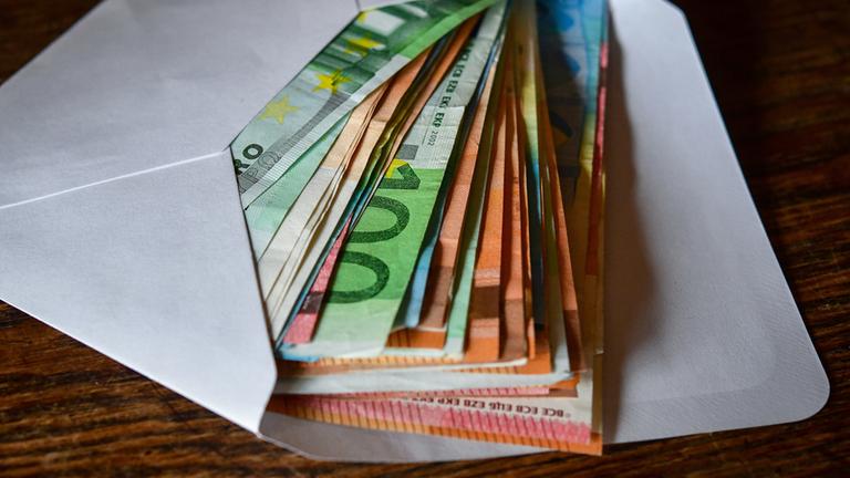 Brandenburg, Sieversdorf: Viele Eurobanknoten liegen in einem Briefumschlag auf einem Tisch. 