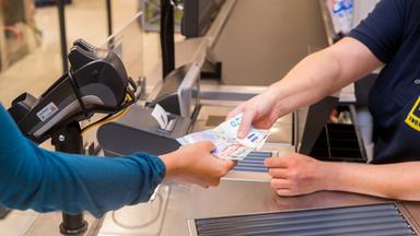 Schleswig-Holstein, Flensburg: In einem Supermarkt hebt eine Kundin beim Bezahlen auch gleich Bargeld ab. Archivbild