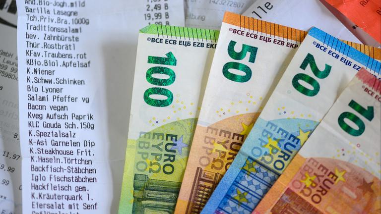 Sachsen, Leipzig: Geldscheine liegen auf Kassenzettel.