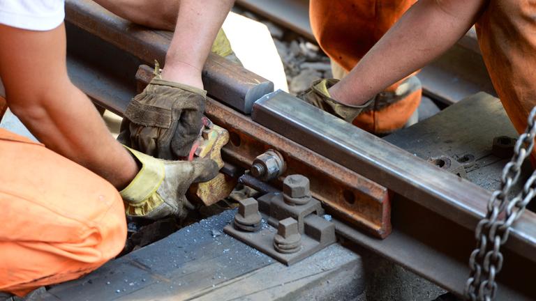 Zwei Arbeiter die Arbeiten am Gleis verrichten.