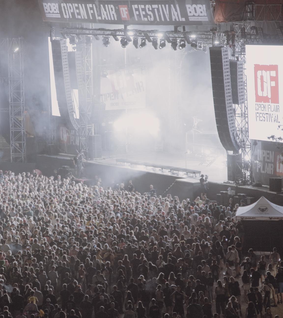 Beim Open Flair Festival haben sich bei Nacht vor der großen, hellerleuchteten Bühne viele Festivalbesucher versammelt.