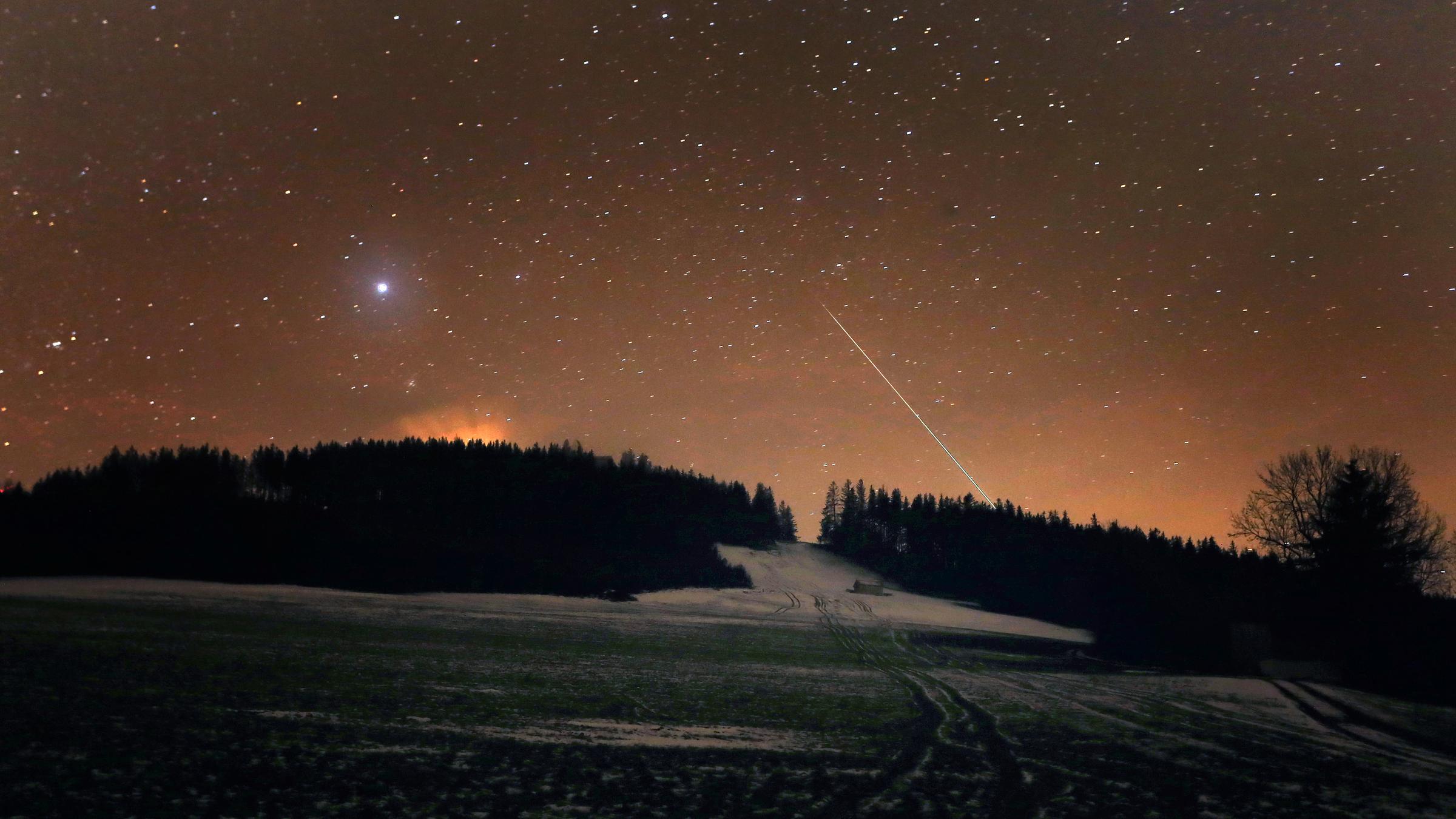 13.12.2020, Bayern, Stötten: Eine Sternschnuppe verglüht am Nachthimmel über dem Auerberg.