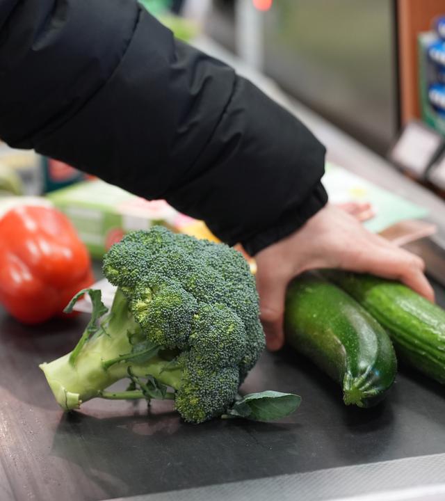 Ein Mann legt seinen Einkauf auf das Laufband an einer Kasse in einem Supermarkt