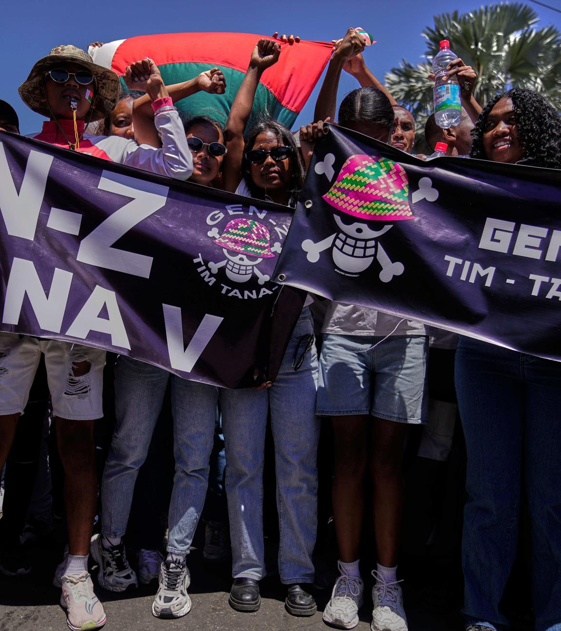 Mehrere Jugendliche und junge Erwachsene halten auf einer Demonstration in Madagaskar Banner und Fahnen.
