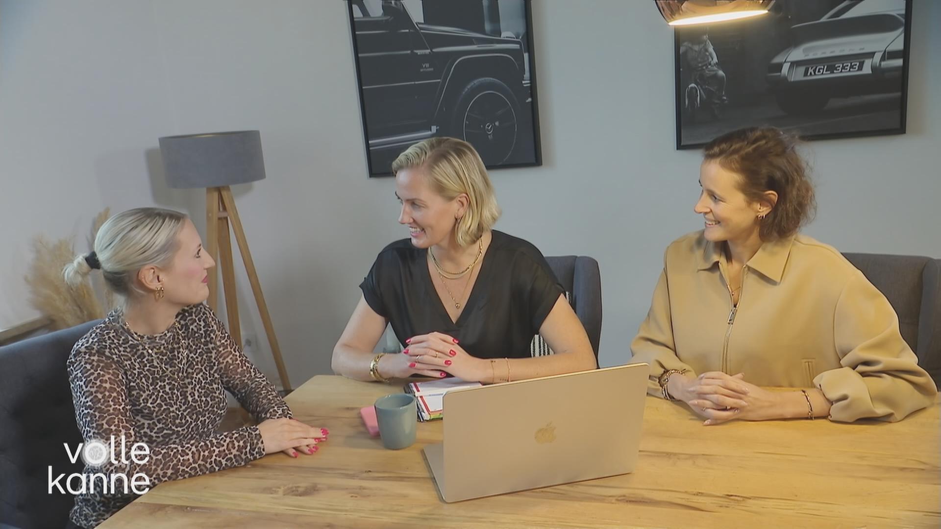 Drei Frauen an einem Tisch unterhalten sich. Auf dem Tisch steht ein Laptop.