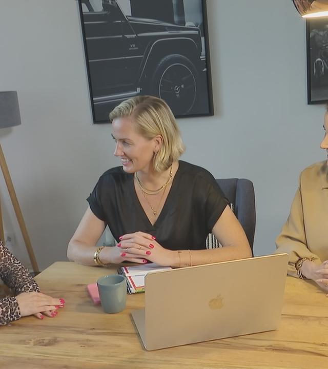 Drei Frauen an einem Tisch unterhalten sich. Auf dem Tisch steht ein Laptop.