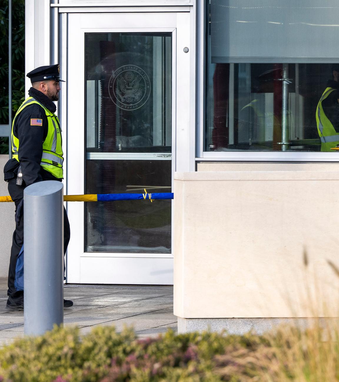 Schweiz, Genf: Ein US-Wachmann geht mit der ukrainischen Flagge vor der Ständigen Vertretung der USA in Genf, Schweiz.