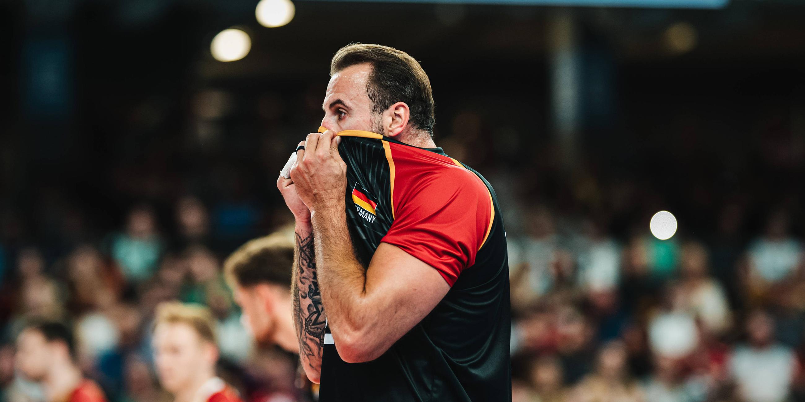 Georg Grozer (Deutschland, 9) zieht sich beim Volleyball-Länderspiel gegen Belgien am 23.08.2025 in der LKH-Arena Lüneburg das Trikot über den Kopf.