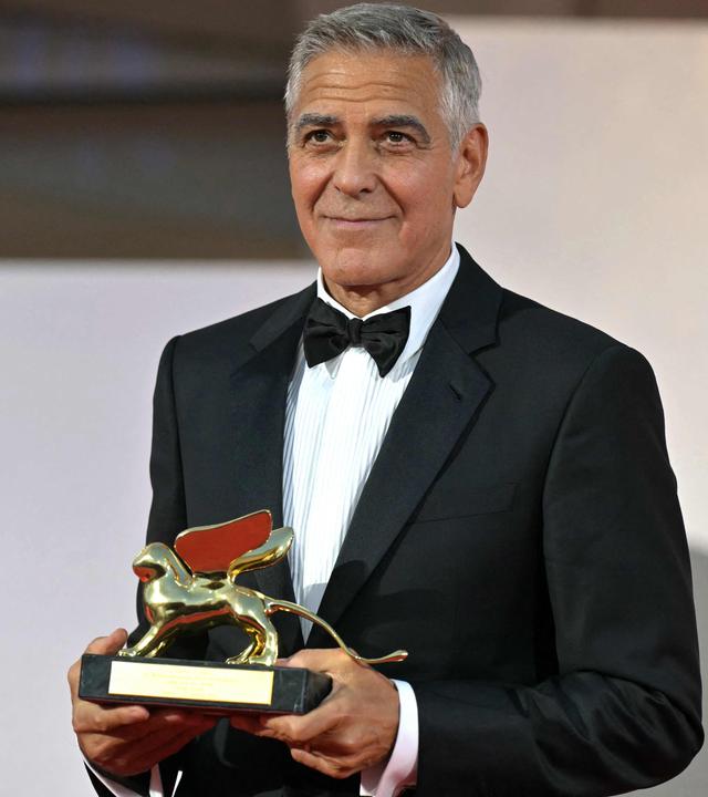 George Clooney posiert mit seinem Preis.