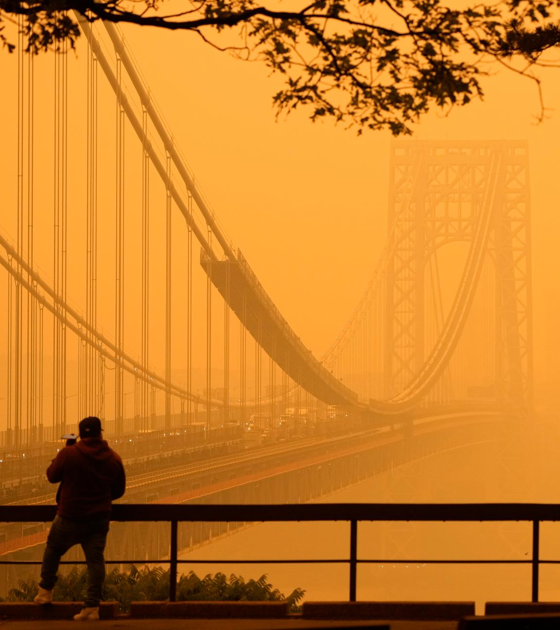 Ein Mann telefoniert, während er durch den Dunst vor der George Washington Bridge sieht.