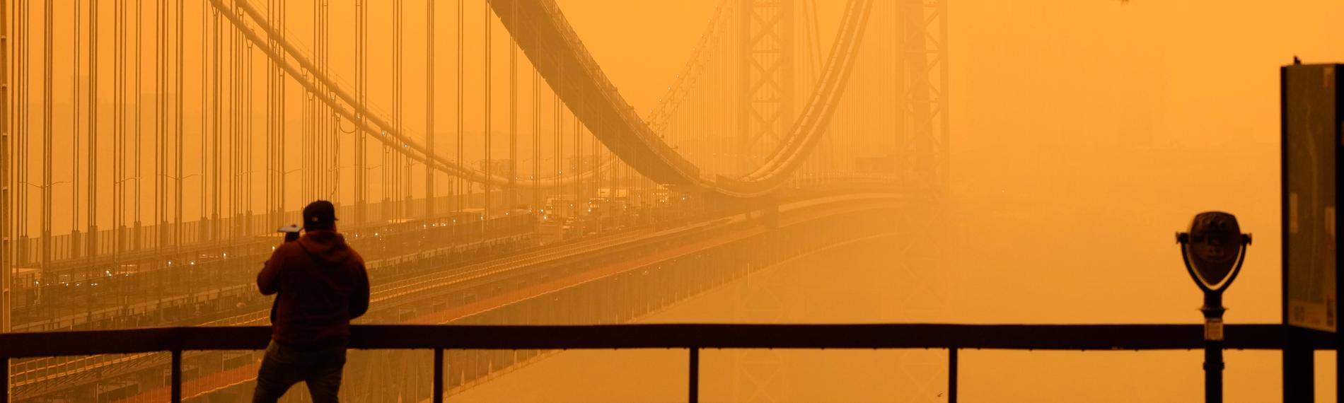 Ein Mann telefoniert, während er durch den Dunst vor der George Washington Bridge sieht.