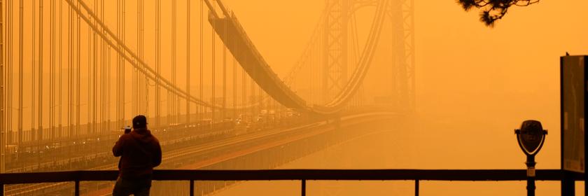 Ein Mann telefoniert, während er durch den Dunst vor der George Washington Bridge sieht.