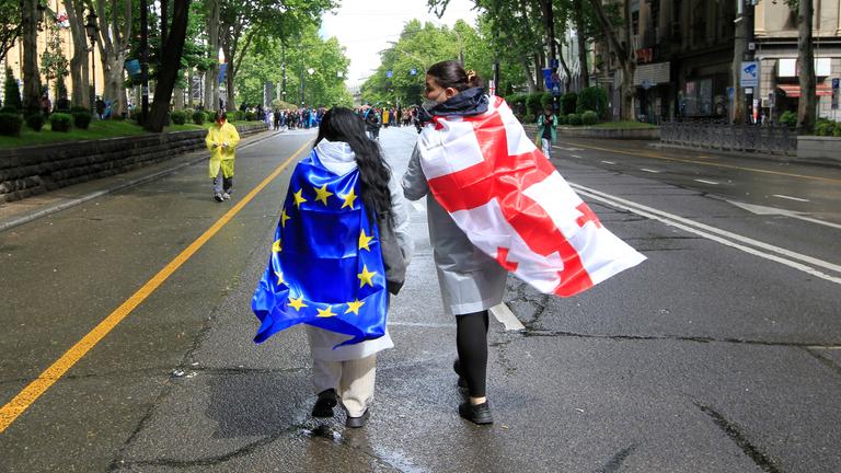 Zwei Demonstranten mit georgischer National- und EU-Flagge gehen während eines Protestes der Opposition gegen das «russische Gesetz» im Zentrum von Tiflis