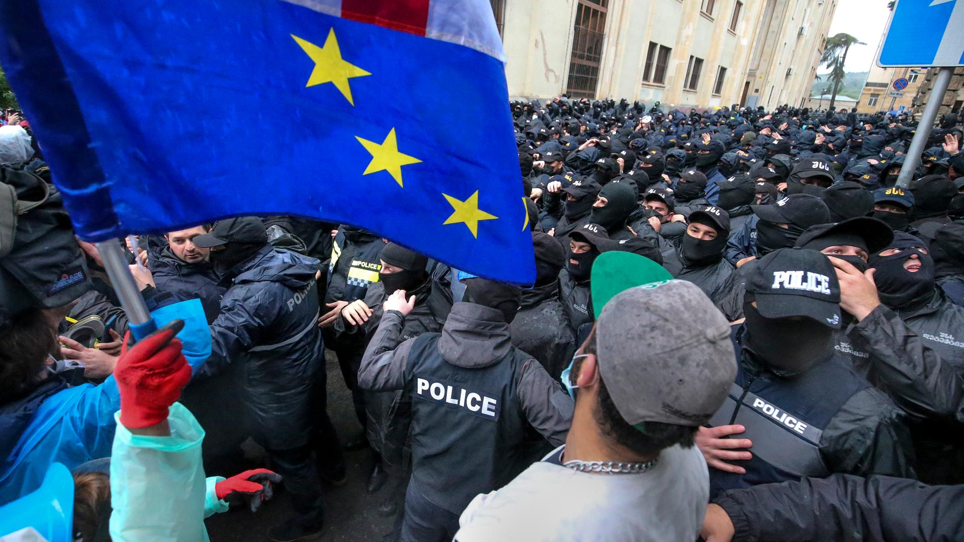 Demonstranten mit georgischen und EU-Flaggen stehen vor einer Polizeisperre in der Nähe des Parlamentsgebäudes in Tiflis