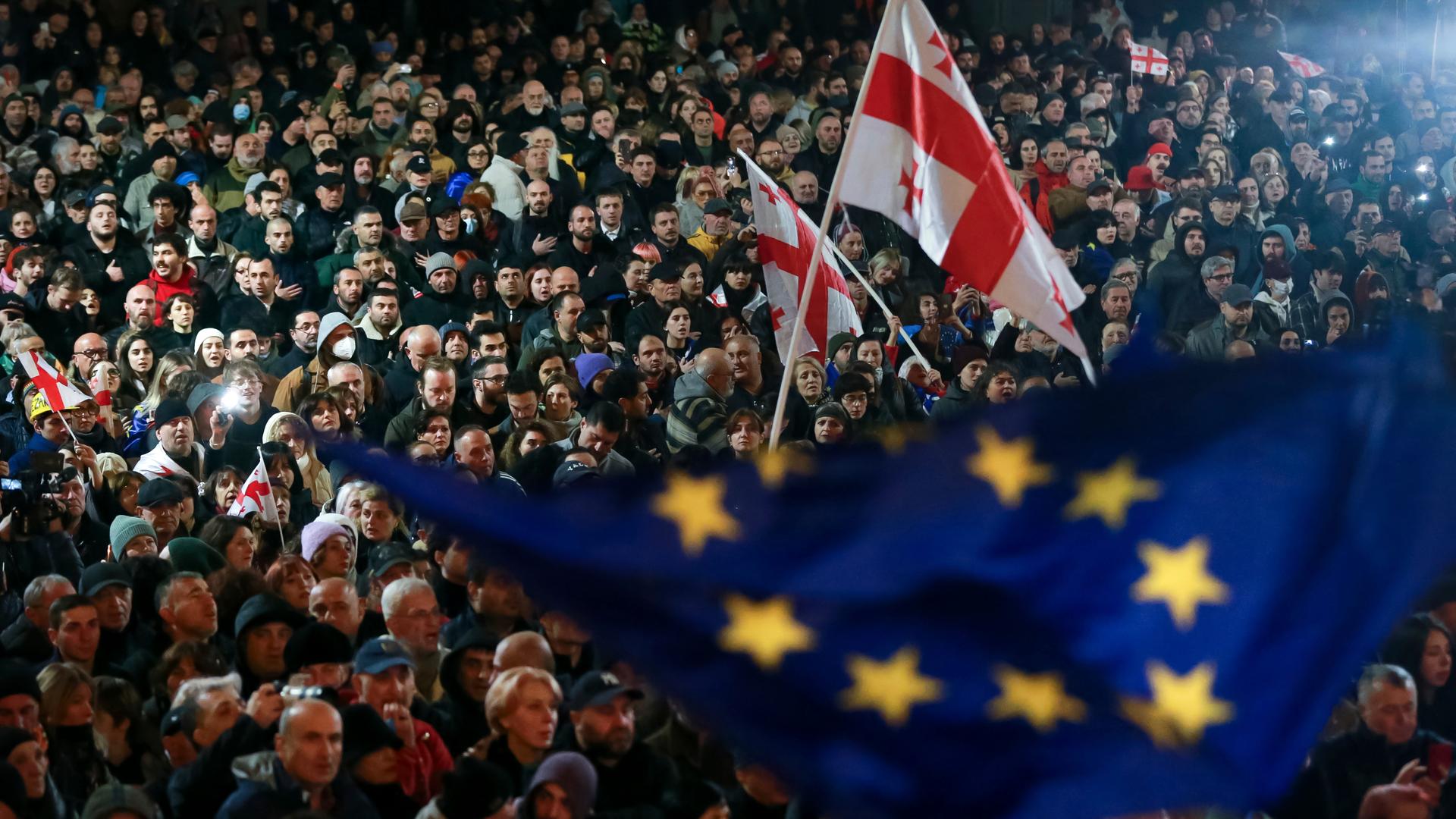 Demonstranten schwenken EU- und georgische Nationalflaggen, während sie an einer Kundgebung gegen angebliche Verstöße bei den jüngsten Parlamentswahlen teilnehmen.