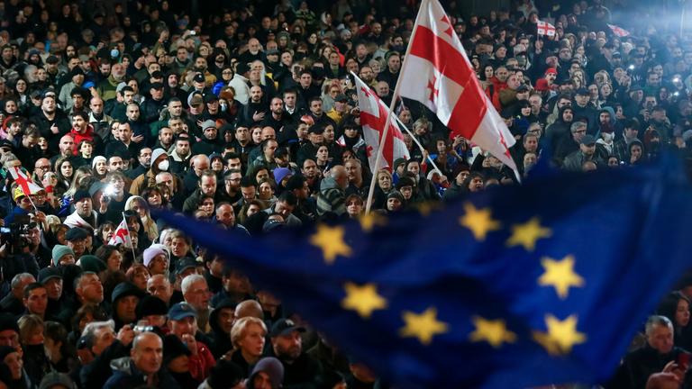 Demonstranten schwenken EU- und georgische Nationalflaggen, während sie an einer Kundgebung gegen angebliche Verstöße bei den jüngsten Parlamentswahlen teilnehmen.