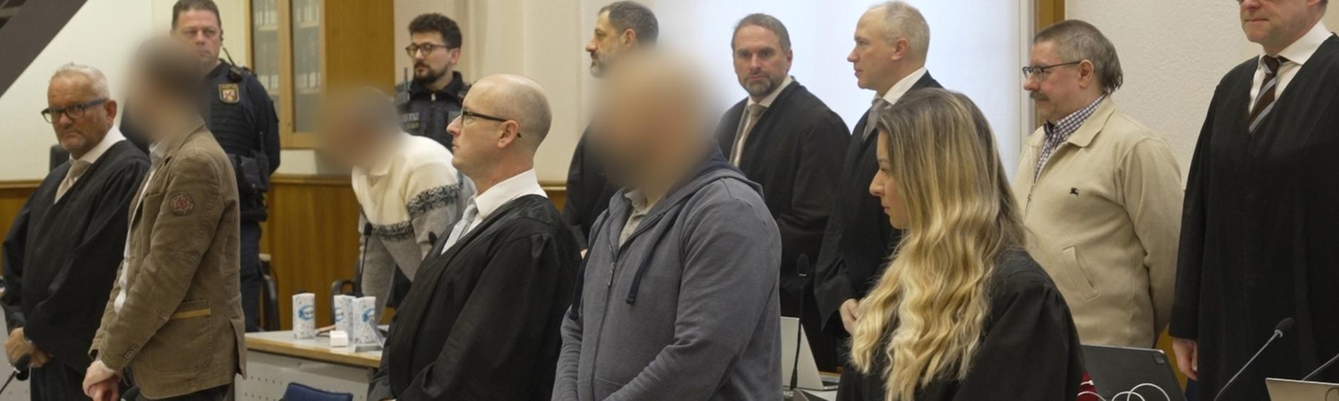 Die Angeklagten und ihre Anwälte stehen auf, als das Gericht den Saal betritt. 