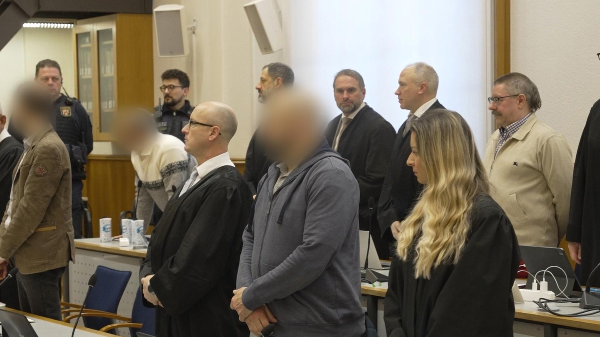 Die Angeklagten und ihre Anwälte stehen auf, als das Gericht den Saal betritt. 