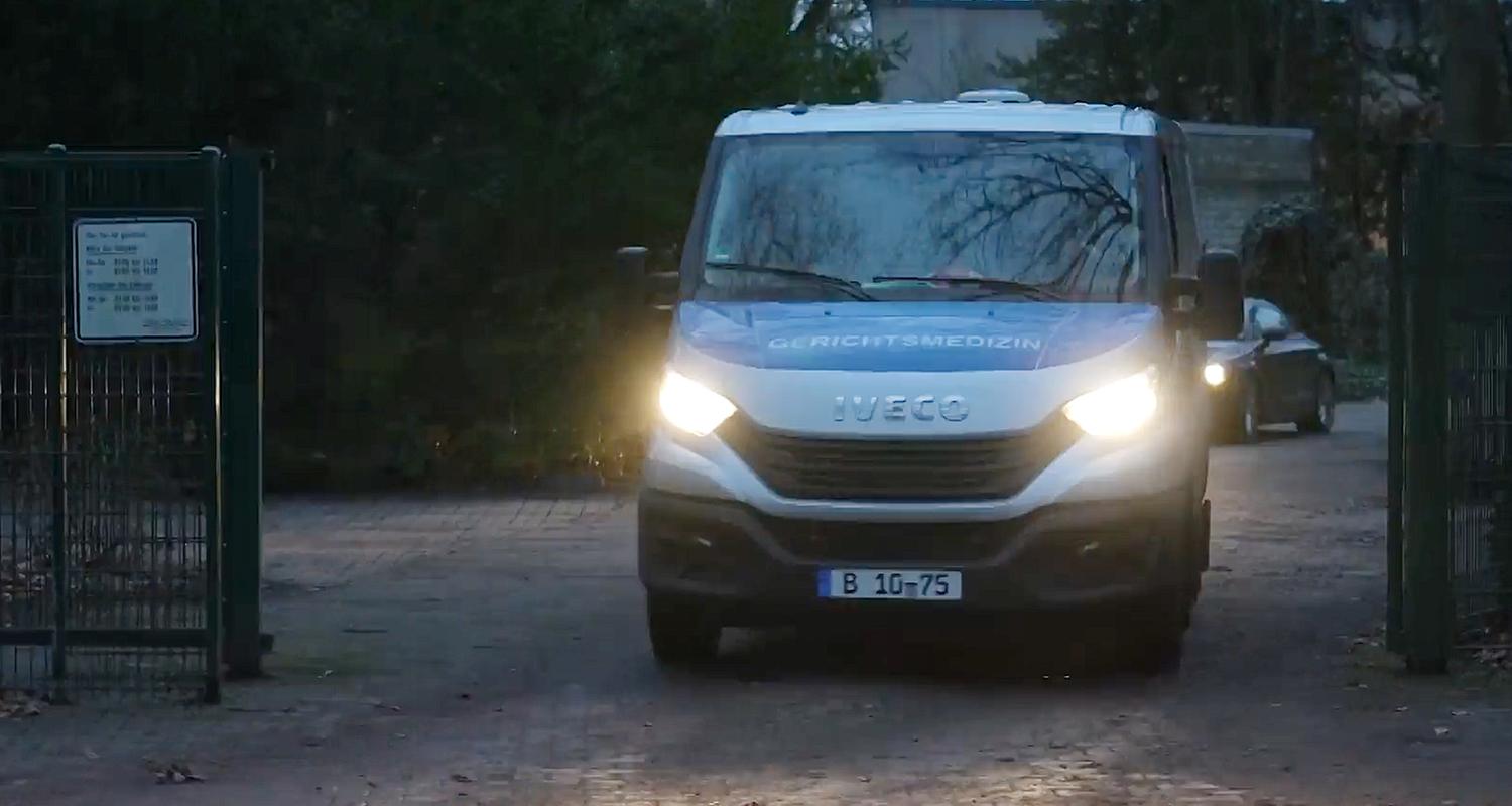 Ein Fahrzeug der Gerichtsmedizin verlässt einen Friedhof.