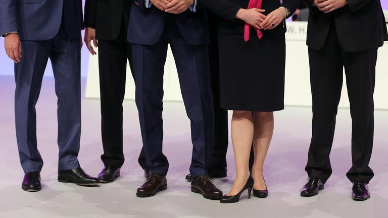 illlustration - mehrere maennliche und ein weibliches vorstandsmitglied stehen zusammen auf dem podium.