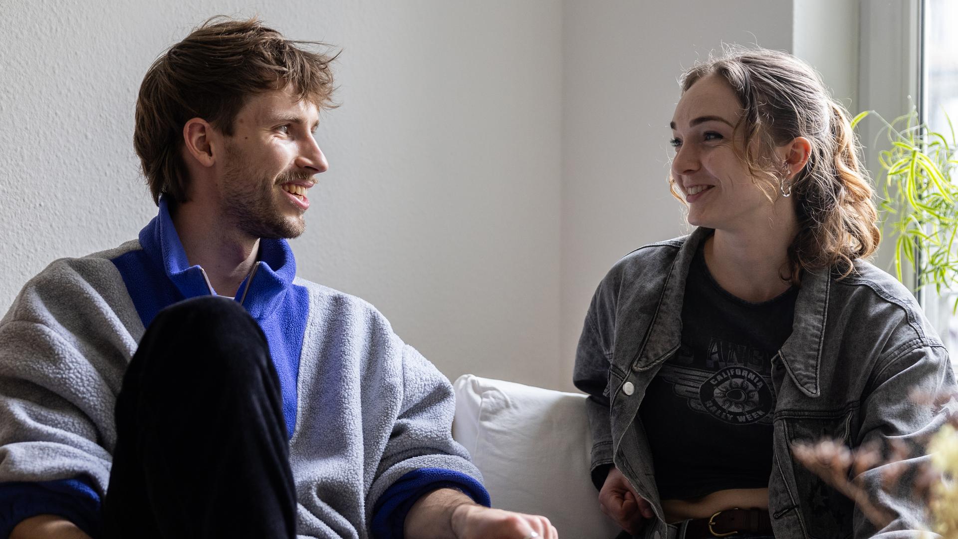 Ein Mann und eine Frau sitzen auf einem Sofa und unterhalten sich.