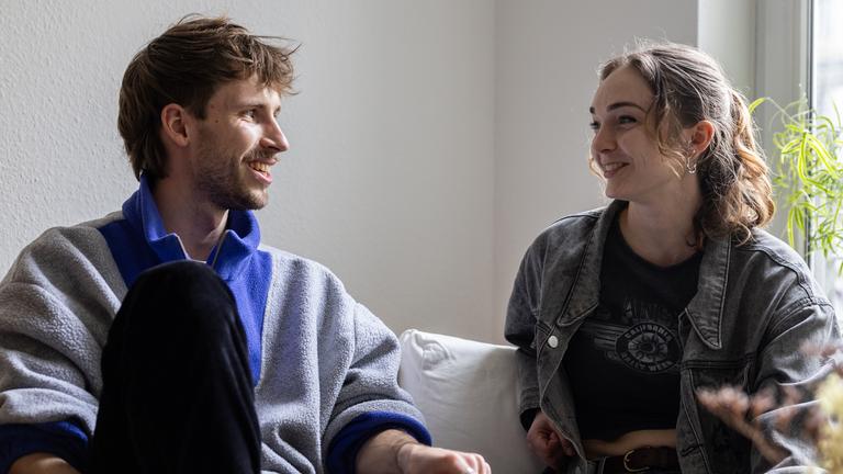 Ein Mann und eine Frau sitzen auf einem Sofa und unterhalten sich.