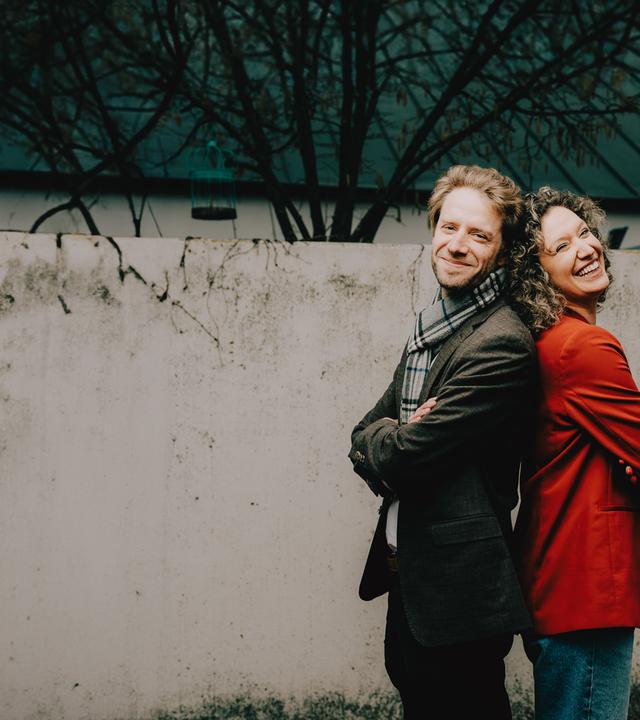 Anna und Sebastian stehen Rücken an Rücken.