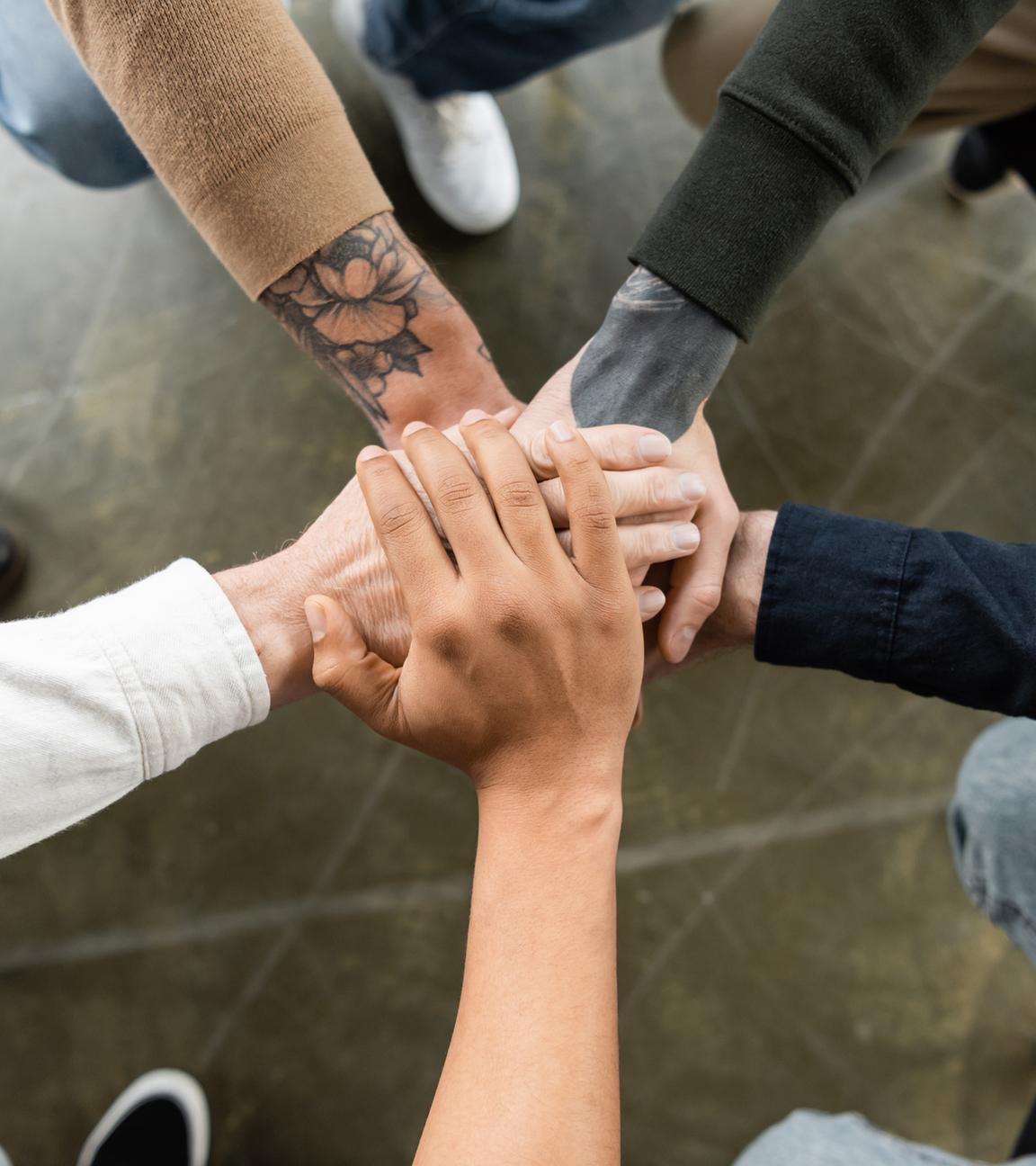 Blick von oben auf multiethnische Menschen, die sich die Hände reichen.