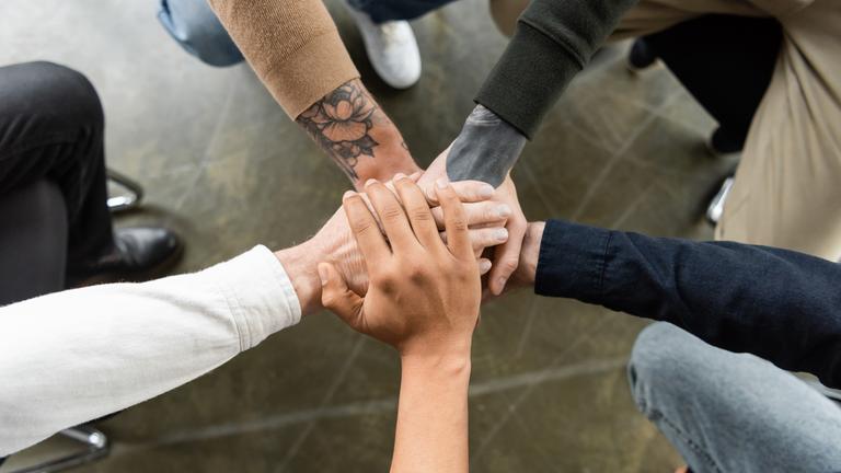 Blick von oben auf multiethnische Menschen, die sich die Hände reichen.