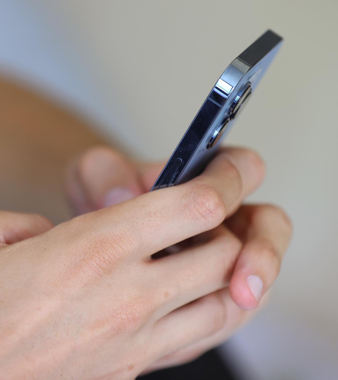 Ein Jugendlicher hält ein Smartphone in den Händen. 