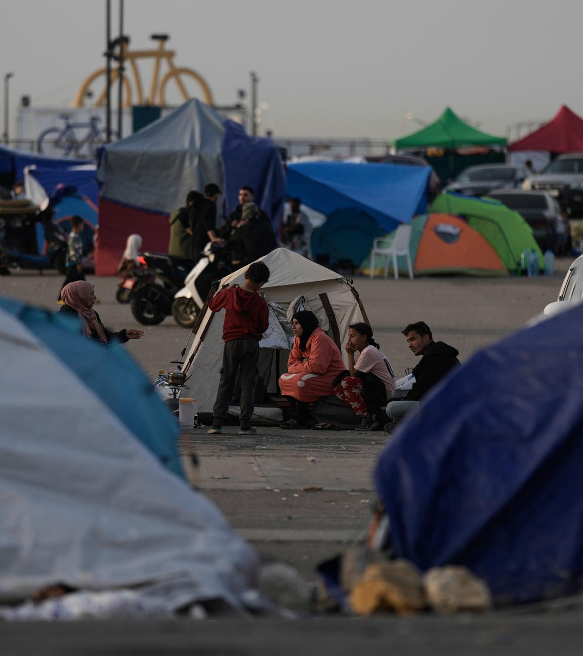 15.04.2026, Libanon, Beirut: Menschen, die vor den israelischen Angriffen auf die als Dahija bekannten südlichen Vororten Beiruts geflohen sind, sitzen vor Zelten, die als Unterkunft dienen.