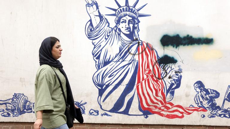 Eine Frau läuft in Teheran an einem Bild an einer Wand vorbei