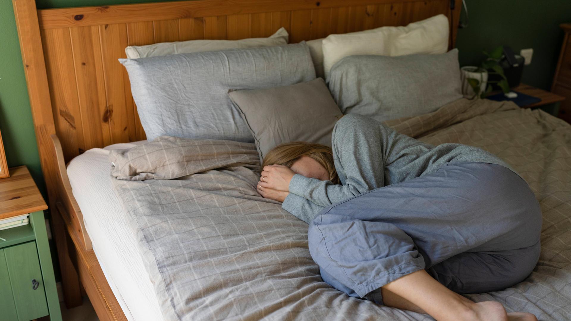 Gestresste Frau liegt zu Hause im Bett