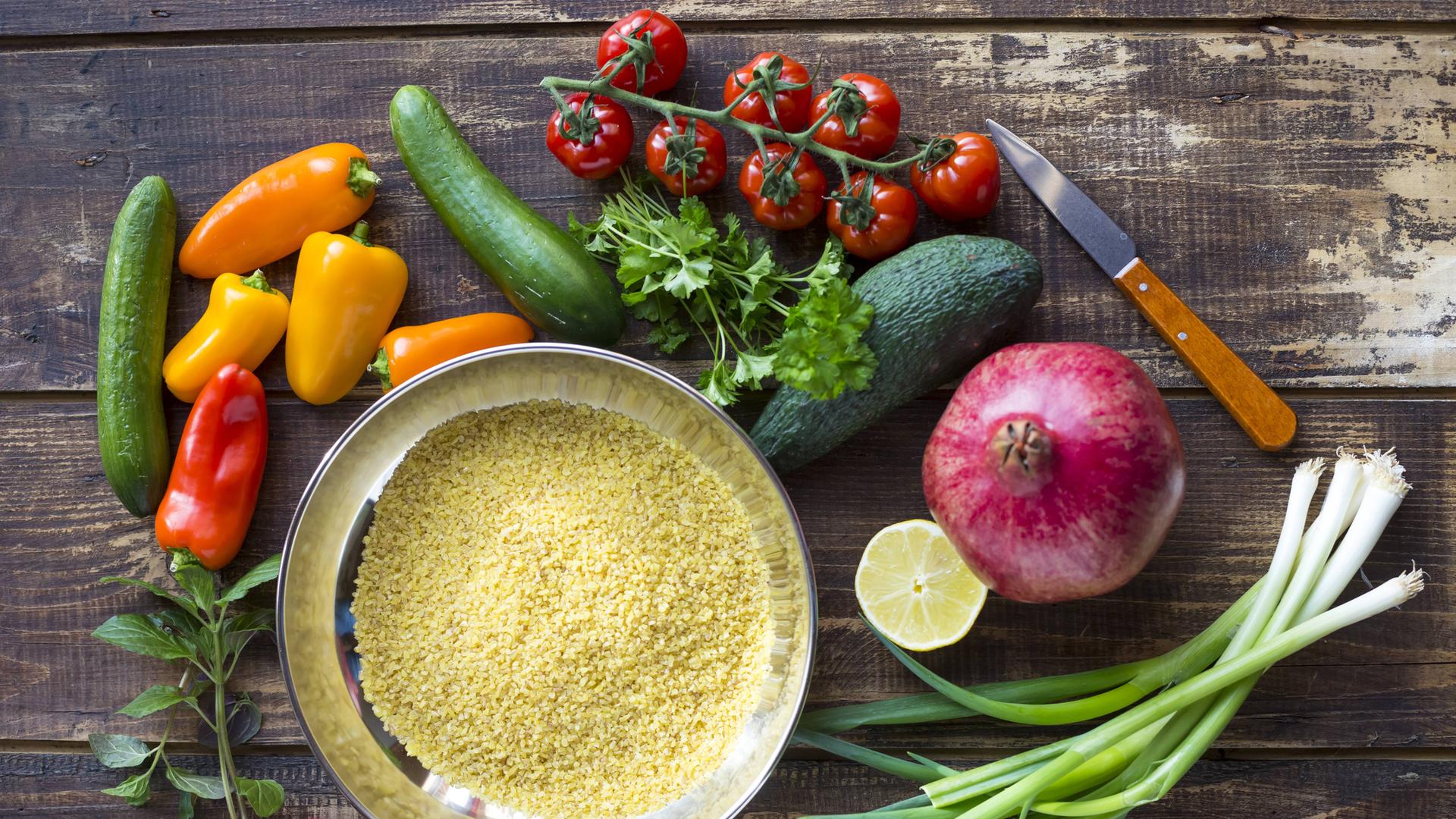 Zutaten für einen Bulgursalat: Bulgur, Paprika, Zucchini, Tomaten, Avocado, Granatapfel, Frühlingszwiebeln, Zitrone, Kräuter