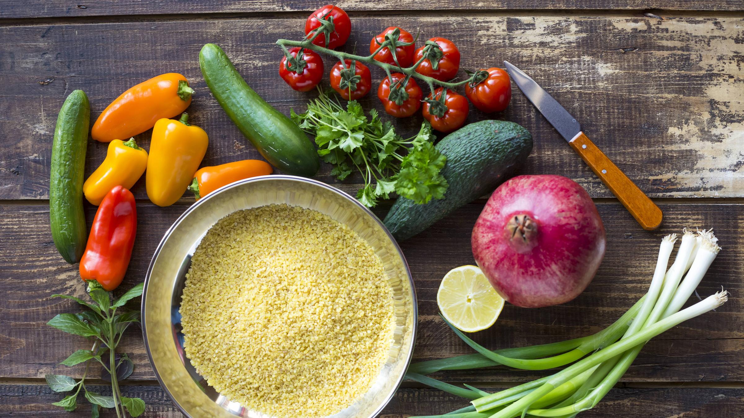 Zutaten für einen Bulgursalat: Bulgur, Paprika, Zucchini, Tomaten, Avocado, Granatapfel, Frühlingszwiebeln, Zitrone, Kräuter