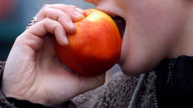 Eine Frau beißt in einen Apfel.