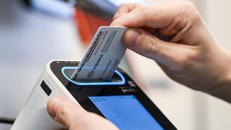  In der E-Health-Showpraxis der Kassenärztlichen Vereinigung Berlin wird eine Gesundheitskarte in ein Lesegerät gesteckt (Gestellte Szene).