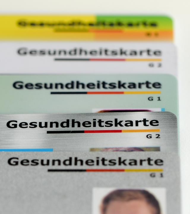 Symbolbild:  Gesundheitskarten verschiedener Krankenkassen liegen auf einem Tisch