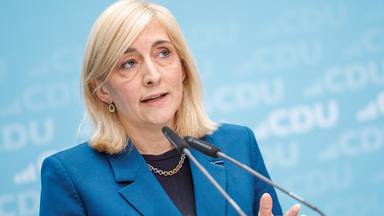 Gesundheitsministerin Nina Warken vor einem blauen Hintergrund mit CDU Logos