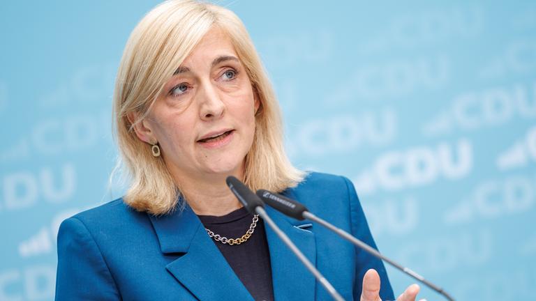Gesundheitsministerin Nina Warken vor einem blauen Hintergrund mit CDU Logos